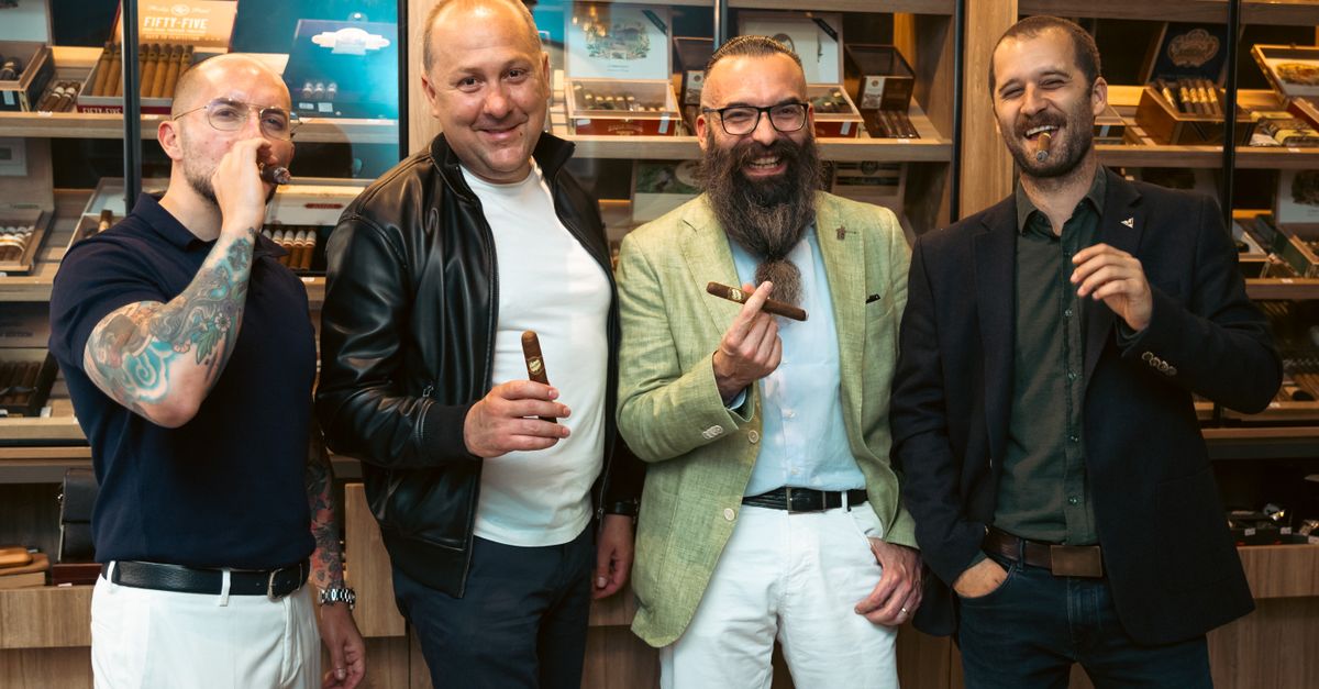 Four men in a cigar lounge enjoying cigars together, exuding a sophisticated and fun atmosphere.